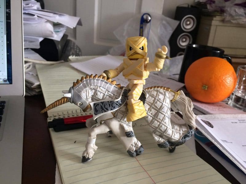 Rob Borkowski] Iron Maiden Eddie Action Figure, astride a plastic horse on his desk.